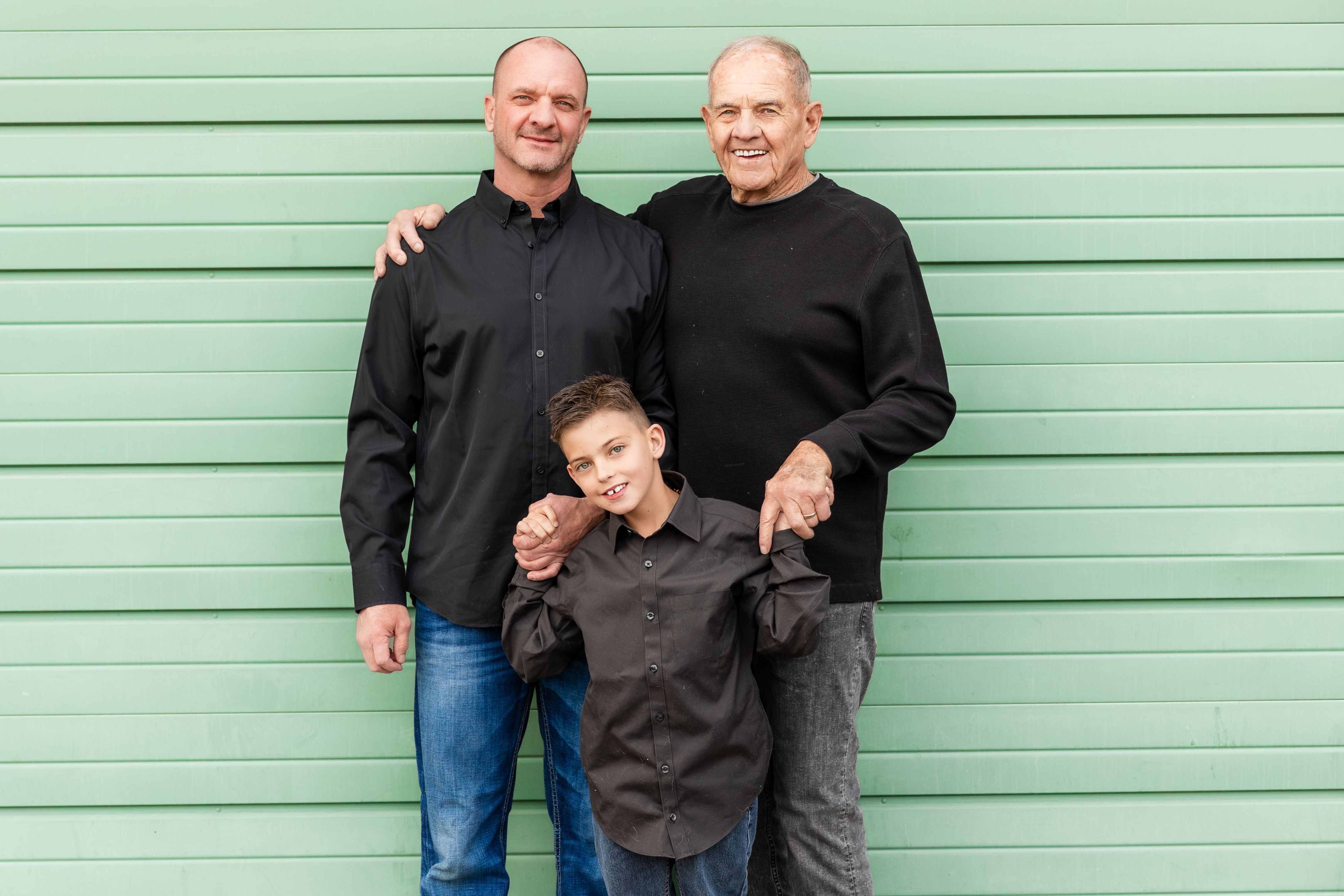 Three generations of the Holmes family in front of a green garage door
