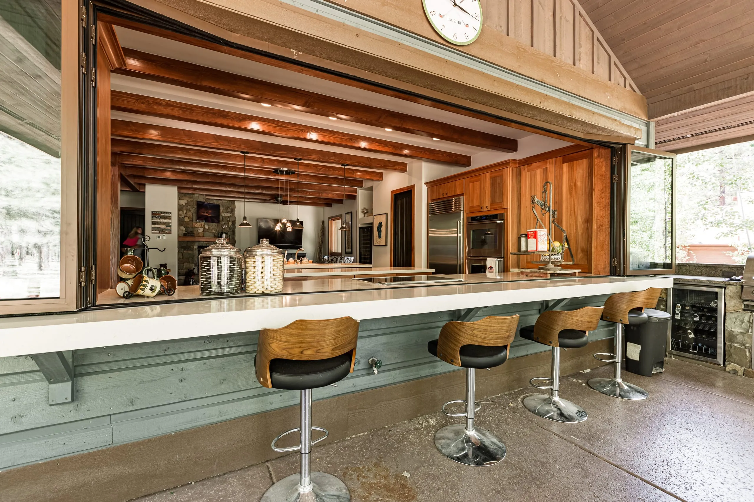 Outdoor kitchen bar with swivel stools and a pass-through window into the kitchen