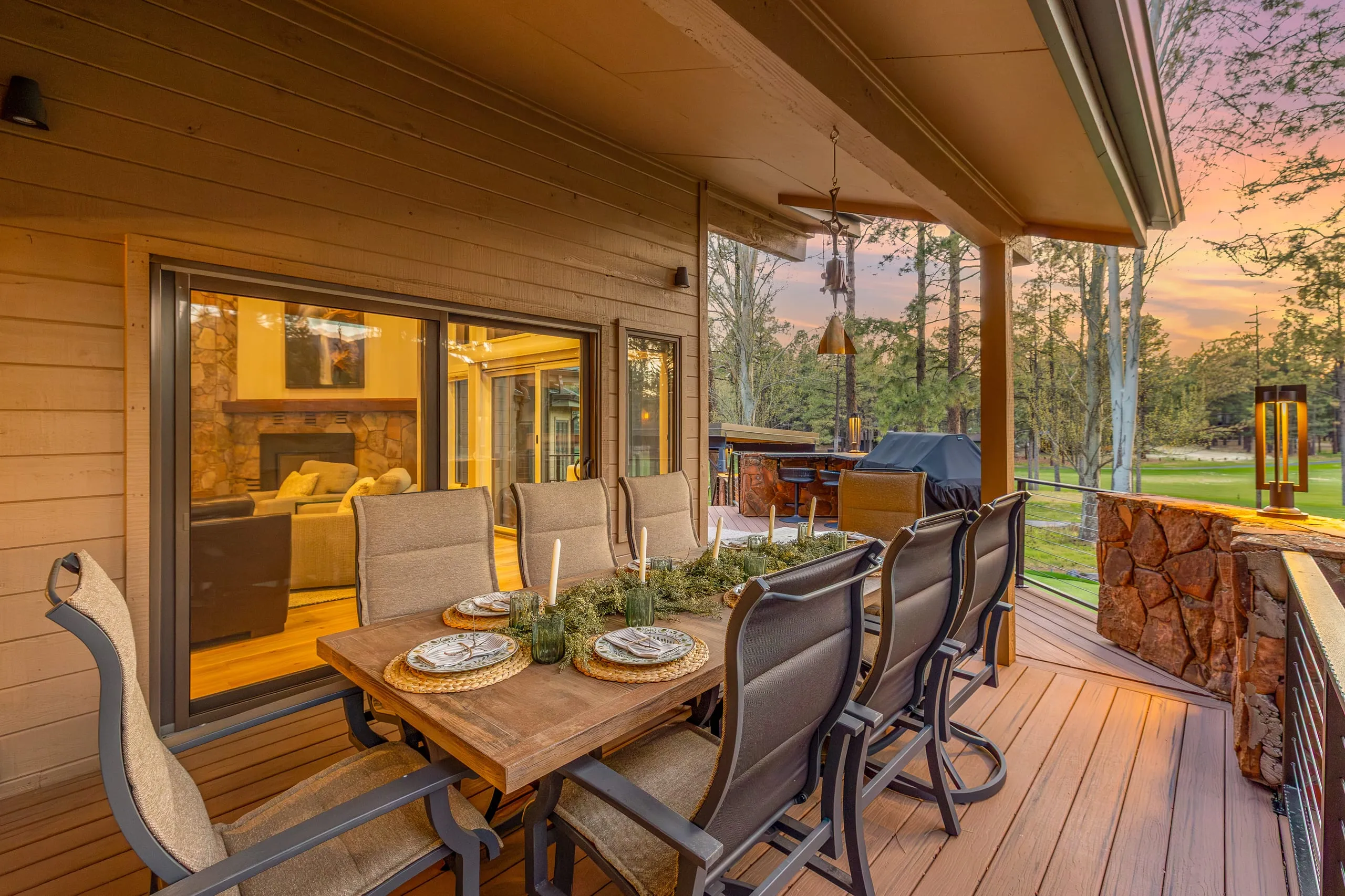 Covered patio dining table set at sunset beside a lawn
