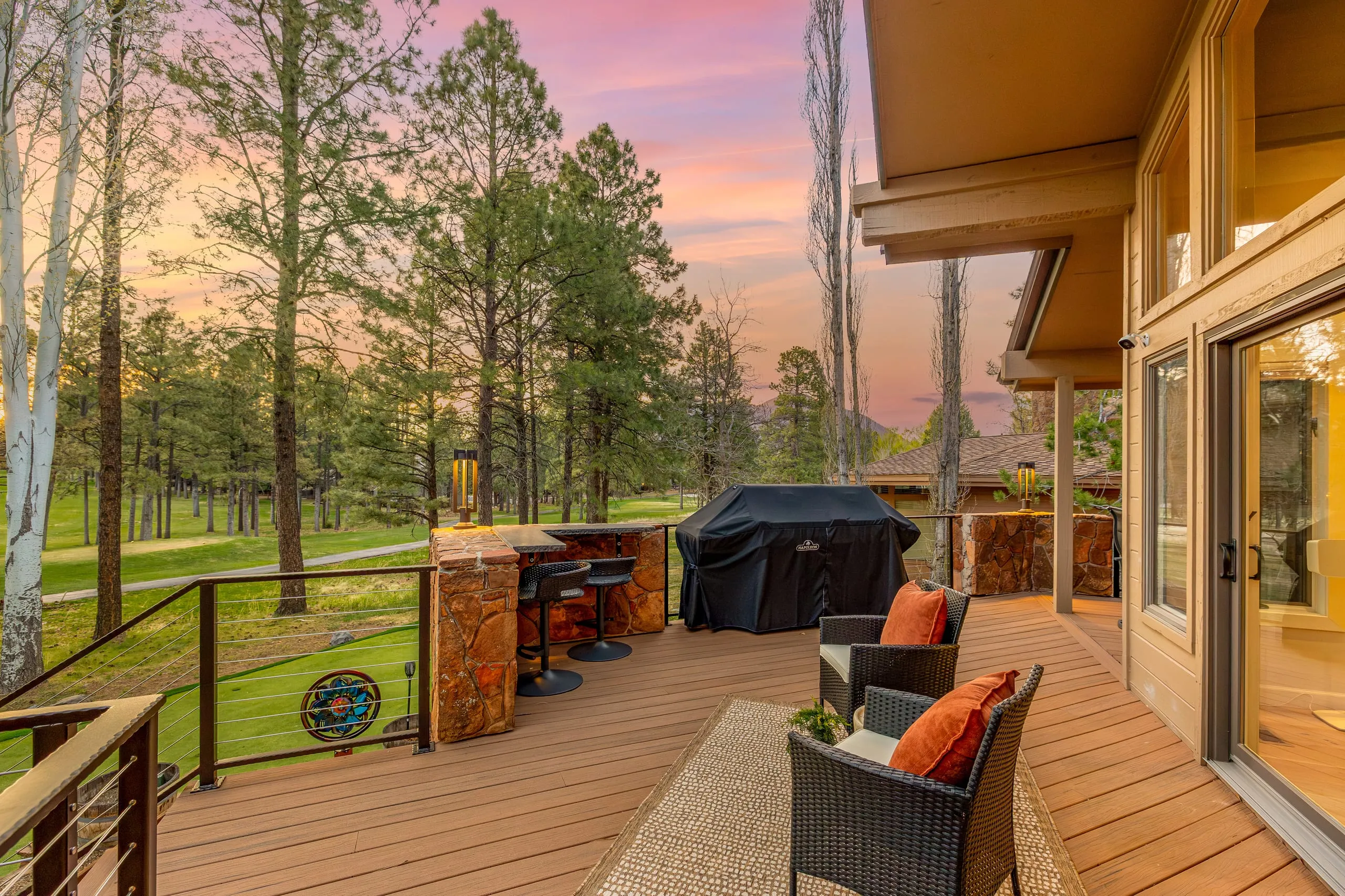 Deck with an outdoor kitchen, grill and lounge chairs at dusk