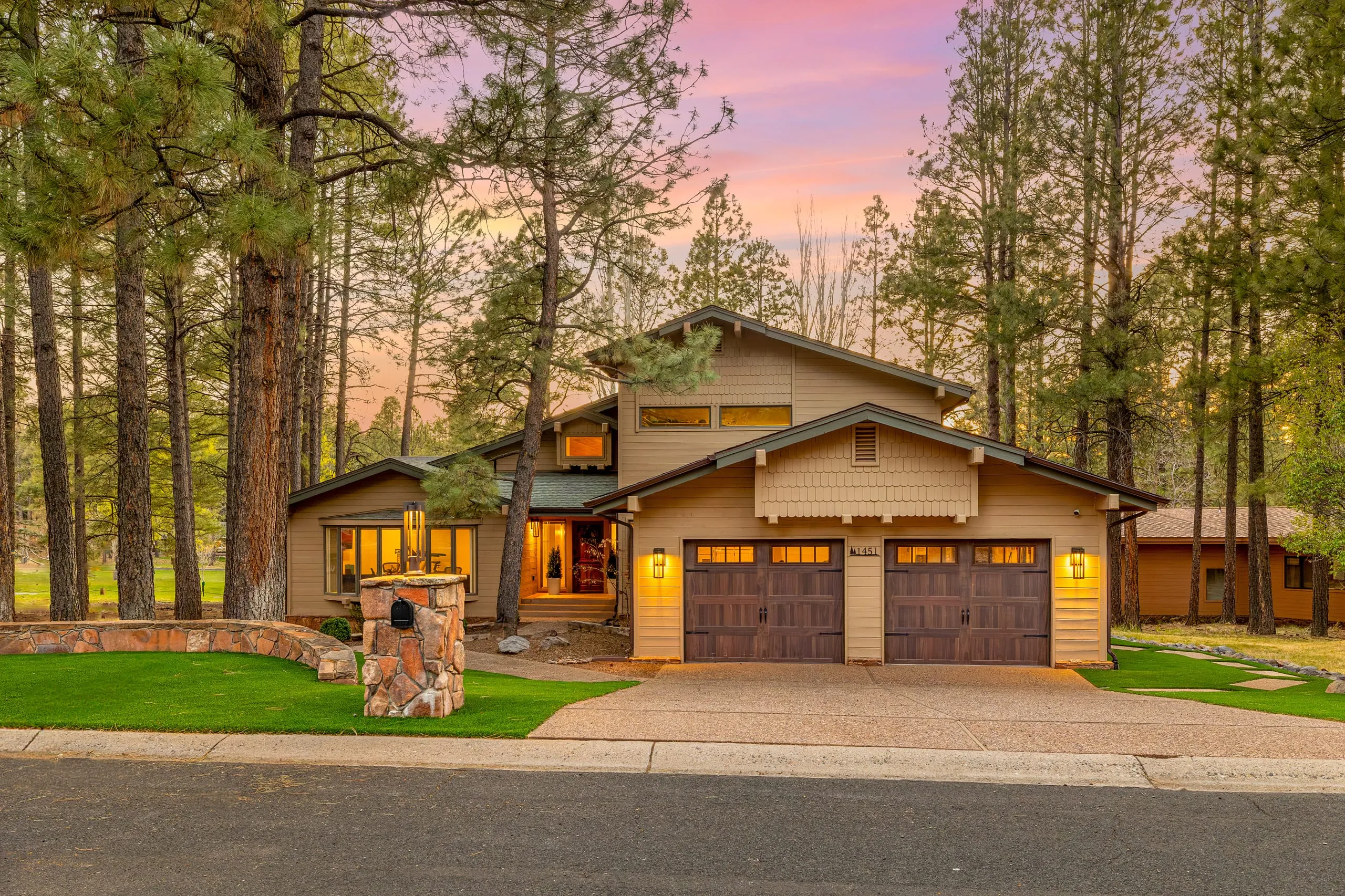 Craftsman home with a stone-columned two-car garage at sunset