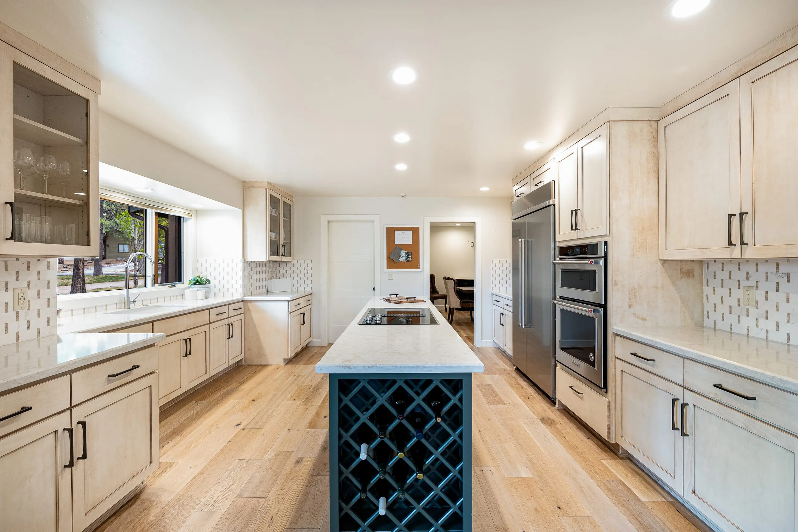 Kitchen with light maple cabinets and a navy island with built-in wine storage