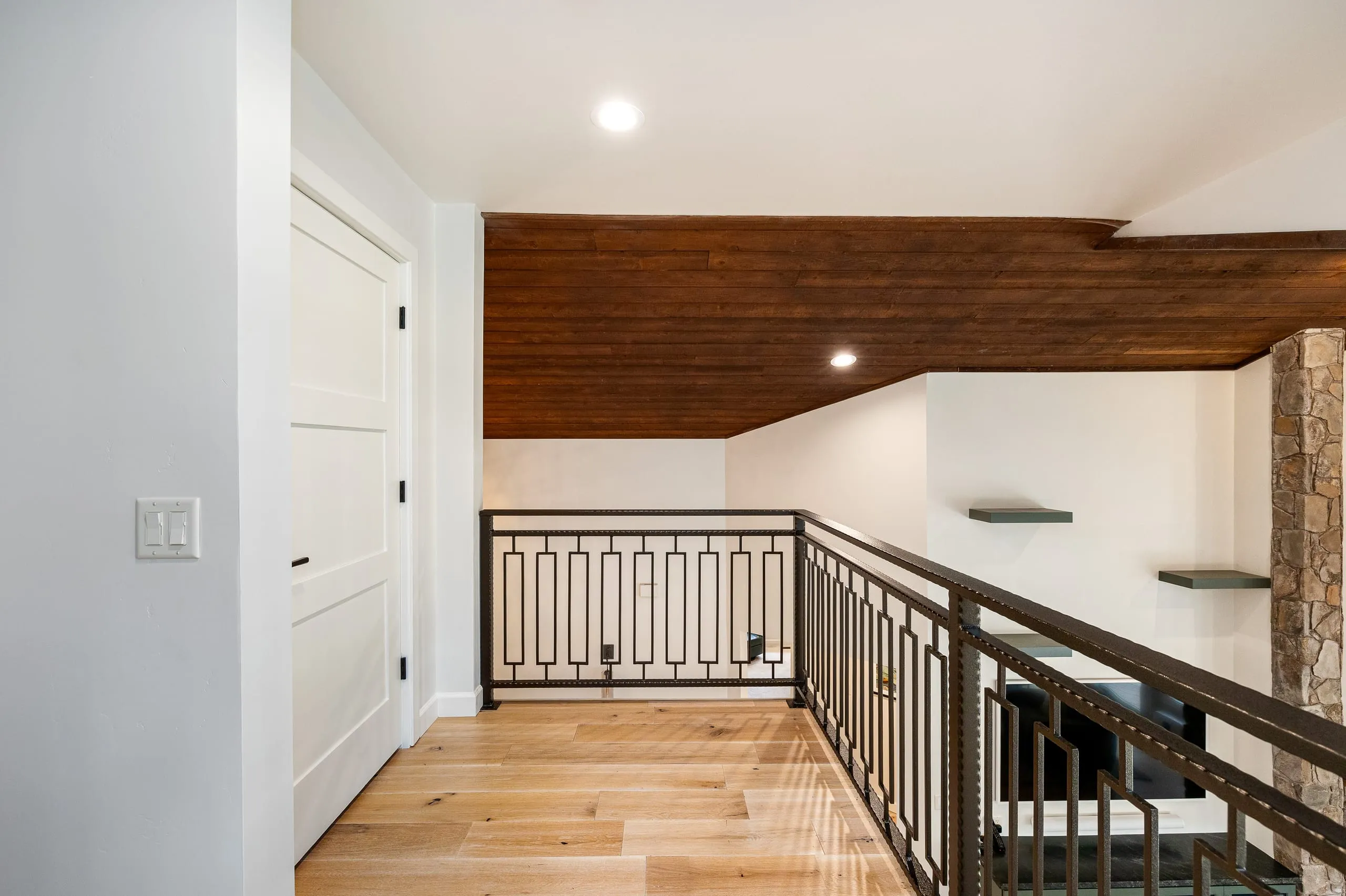 Upstairs landing with a wrought-iron railing and a wood-paneled ceiling