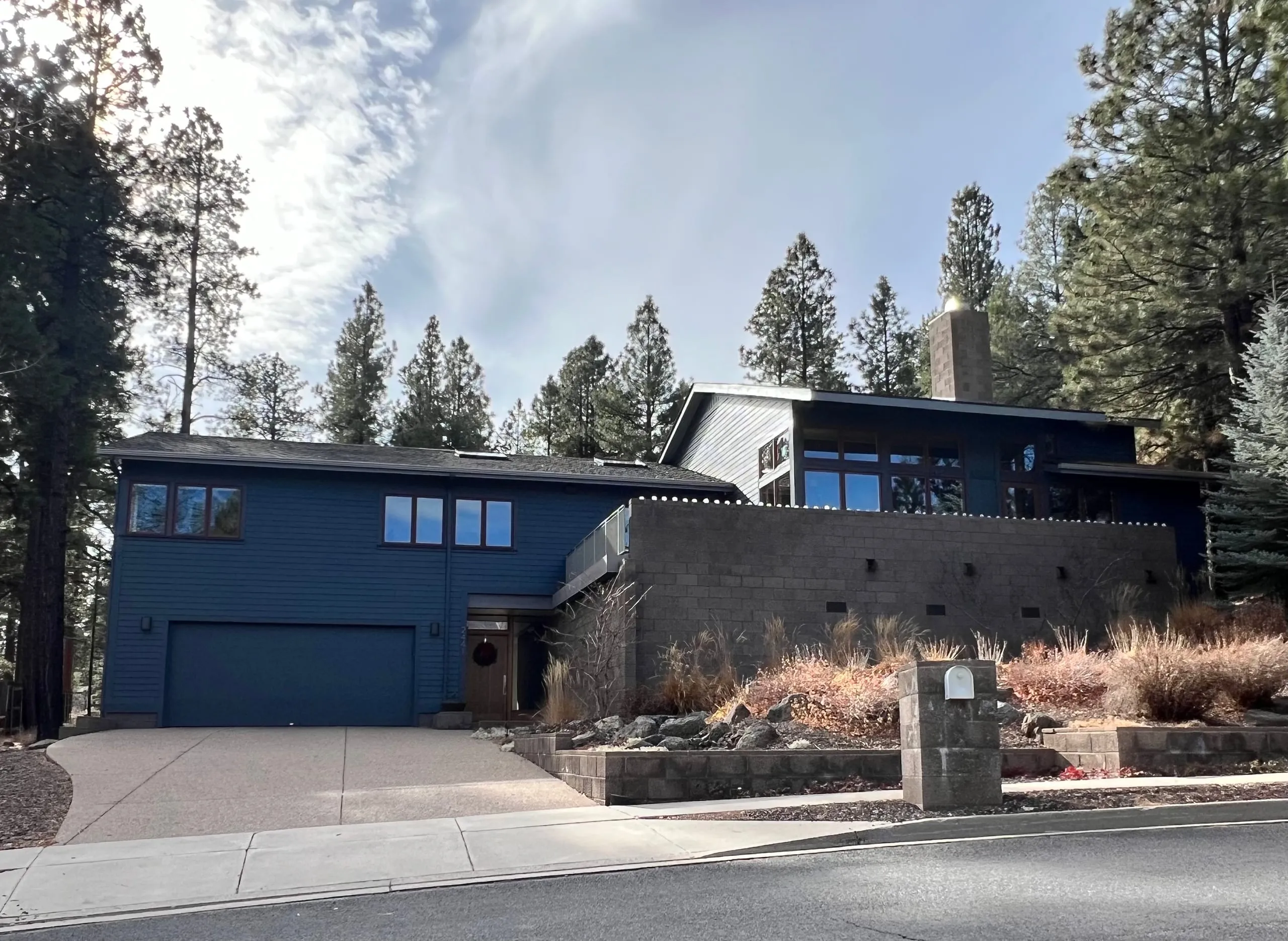 Blue-gray modern home with a garage and a stone retaining wall