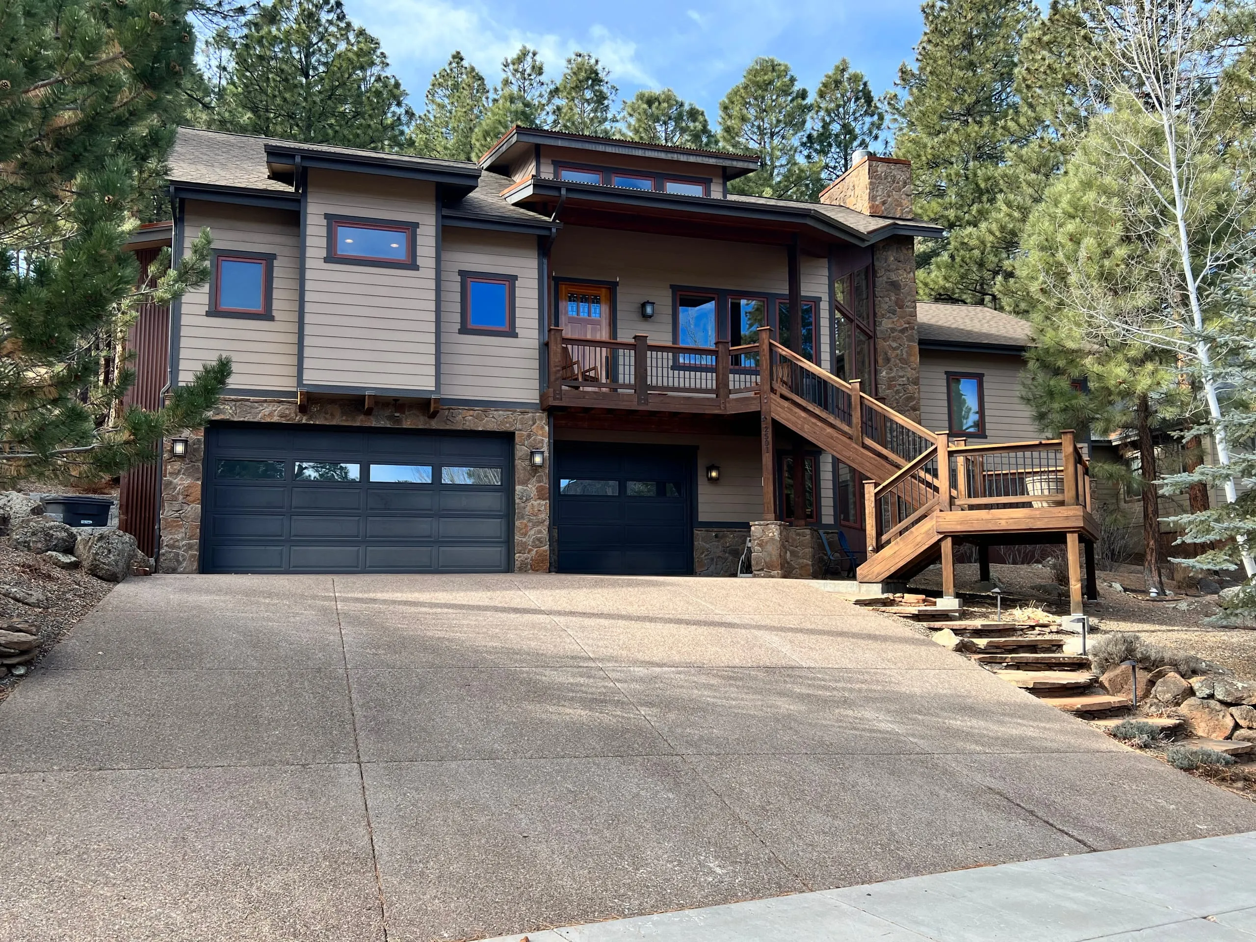Modern two-story home with a black garage door and exterior stairs