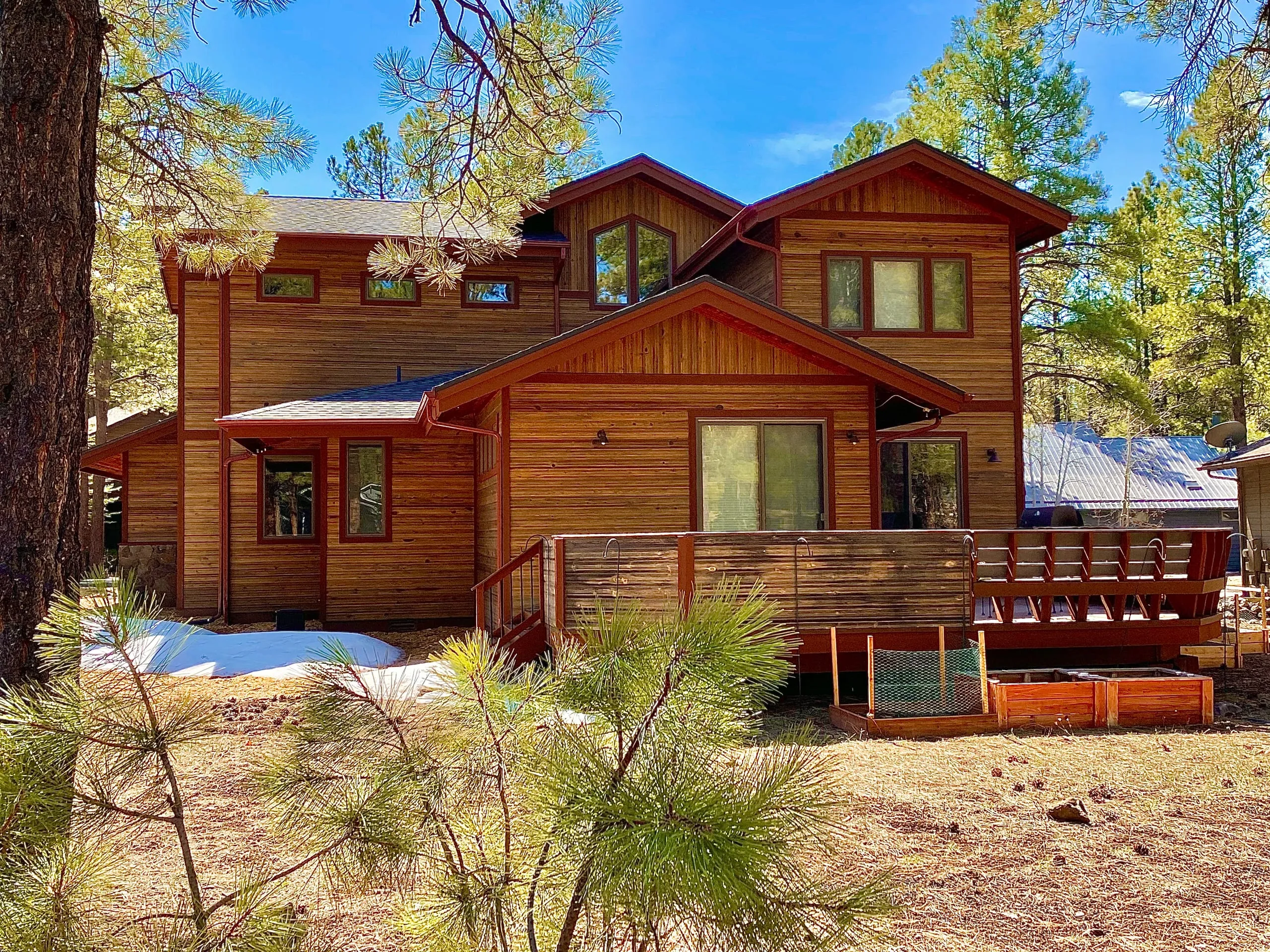 Cedar-sided two-story home with a wide deck among the pines