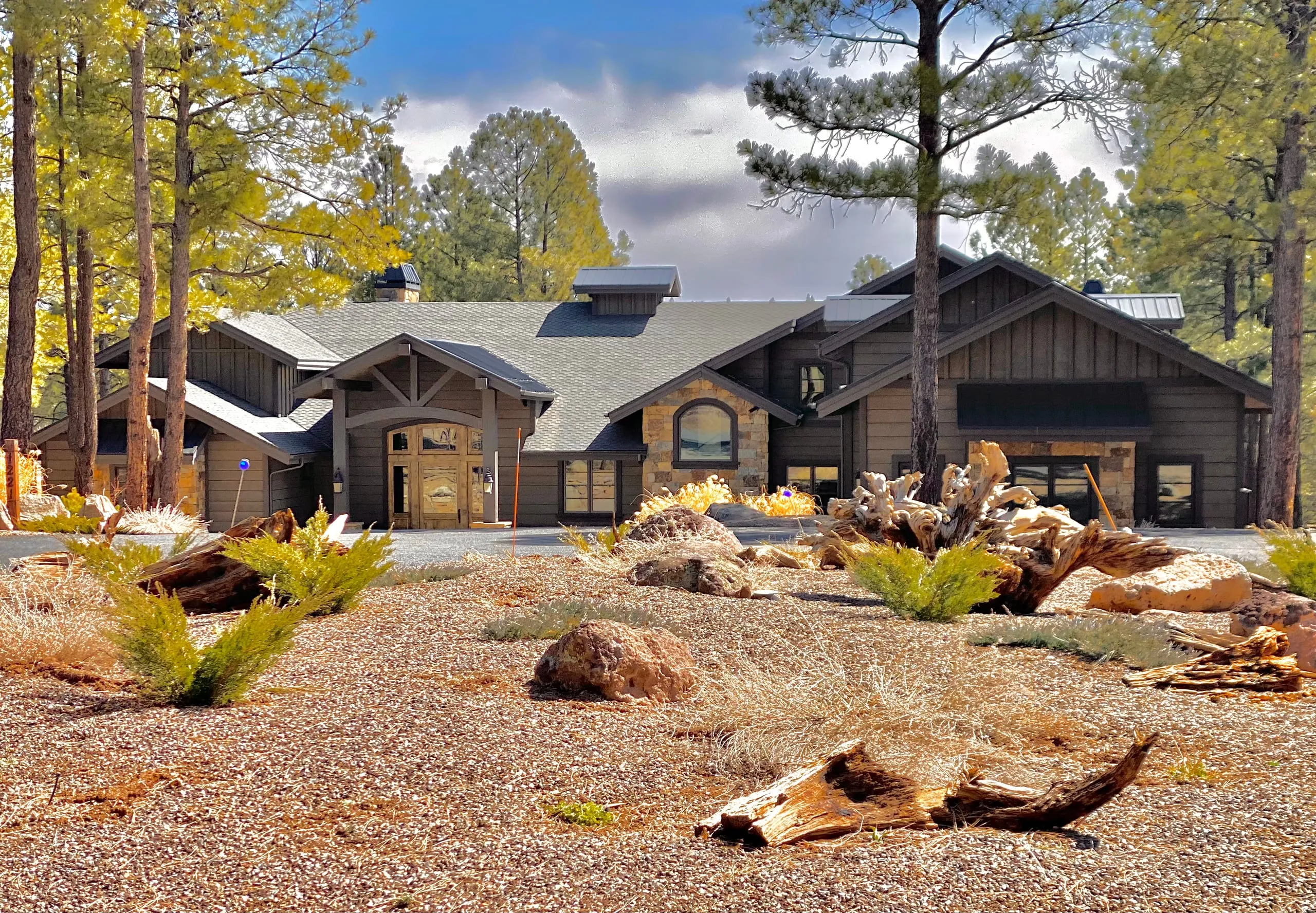 Single-story stone and timber home behind native landscaping